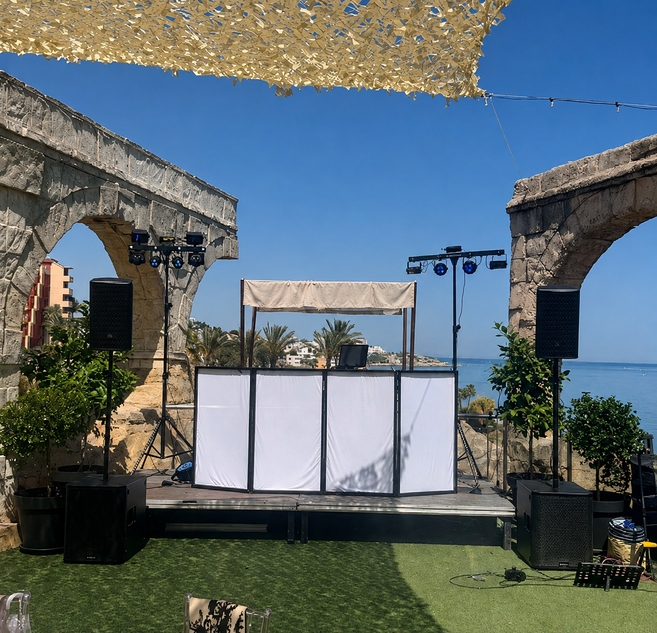 Montaje exterior de BerGi Dj entre arcos de piedra, con el mar de fondo